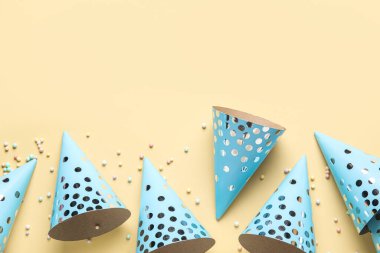 Sarı arka planda parti şapkaları ve konfeti