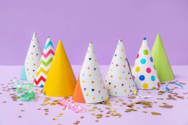 Leylak arkaplanda parti şapkaları ve konfeti