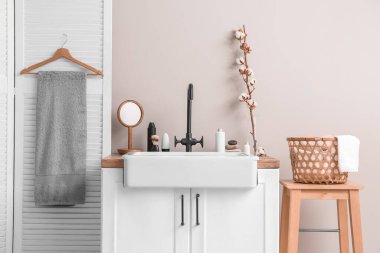 Lavabolu, aksesuarlı ve pamuklu çiçekli bir banyo.