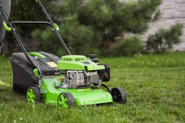 Modern lawn mower on green grass clipart