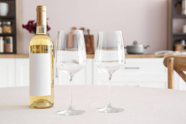 Mutfaktaki yemek masasında bir şişe şarap ve boş bardaklar.