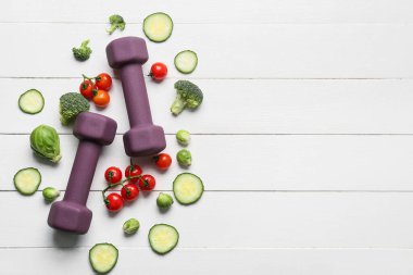 Dambıllar ve taze sebzeler beyaz ahşap arka planda