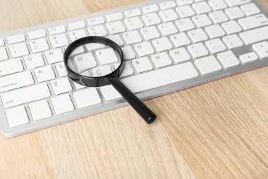 Modern klavye ve büyüteç ahşap masada. İnternet arama kavramı