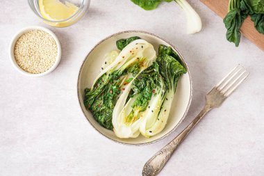 Bir kase lezzetli yahni pak choi lahanası ve hafif arkaplanda susam tohumları.