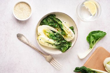 Bir kase lezzetli yahni pak choi lahanası ve hafif arkaplanda susam tohumları.