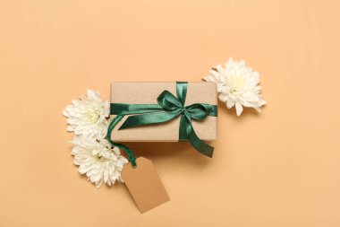 Renkli arkaplanda hediye kutusu, etiket ve kasımpatı çiçekleri olan kompozisyon