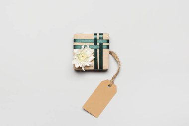 Beyaz arka planda kasımpatı çiçeği ve boş etiketli güzel hediye kutusu