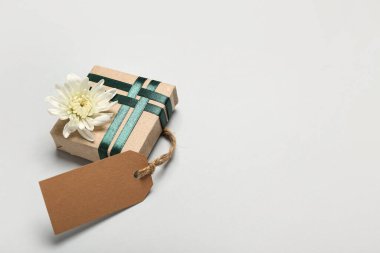 Beyaz arka planda kasımpatı çiçeği ve boş etiketli güzel hediye kutusu