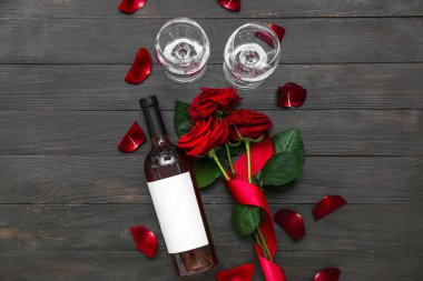 Bir şişe şarap ve koyu ahşap arka planda güller. Sevgililer Günü kutlaması