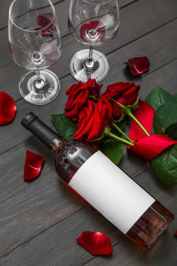 Bir şişe şarap ve koyu ahşap arka planda güller. Sevgililer Günü kutlaması