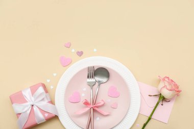 Sevgililer Günü için bej arka planda pembe gül, zarf ve hediye seti.