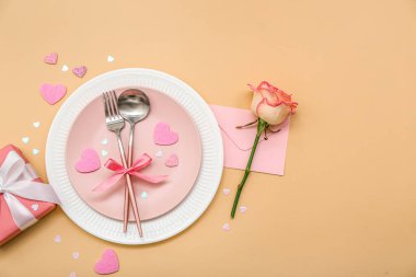 Sevgililer Günü için bej arka planda pembe gül, zarf ve hediye seti.