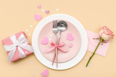 Sevgililer Günü için bej arka planda pembe gül, zarf ve hediye seti.