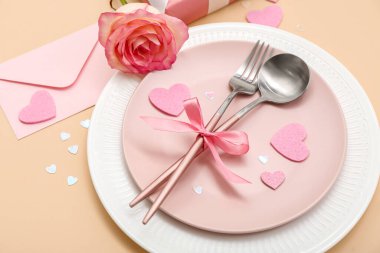 Sevgililer Günü için bej arkaplanda pembe gül ve zarflı masa ayarları