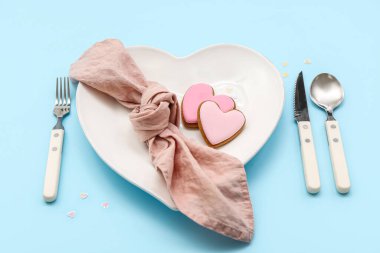 Mavi arka planda pembe kalplerle Sevgililer Günü için masa ayarı