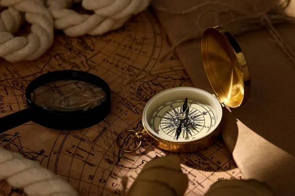 Golden compass, magnifier and envelope on world map
