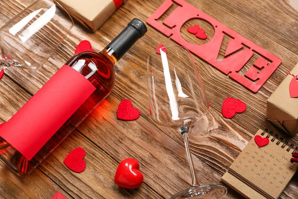 Bottle of wine with glasses and word LOVE on wooden background, closeup. Valentine\'s Day celebration