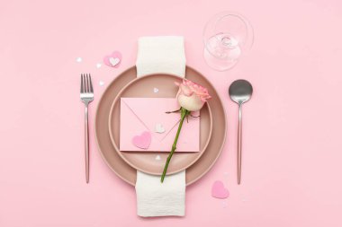 Sevgililer Günü için masa ayarları. Zarflı ve pembe arka planda gül.