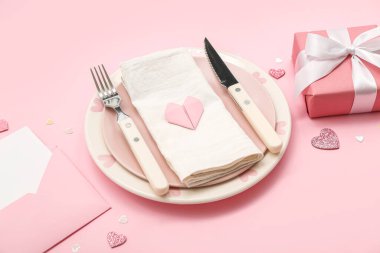 Sevgililer Günü için pembe arka planda bir hediye ve zarf.