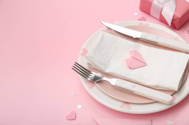 Sevgililer Günü için masa ayarı, pembe arka planda güzel kalpler.