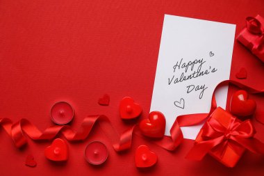 Kırmızı arkaplanda mutlu sonlar, kalpler, hediyeler ve mumlar yazılı kart.