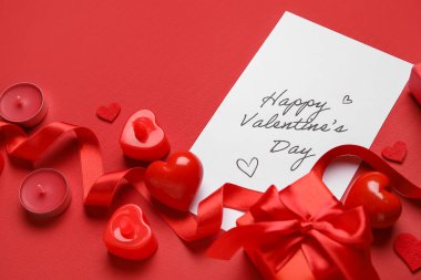 Kırmızı arkaplanda mutlu sonlar, kalpler, hediye ve mumlar yazılı kart.