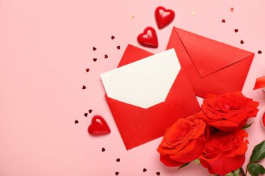 Güllerle dolu boş bir mektup, pembe arka planda kalpler ve şekerler. Sevgililer Günü kutlaması