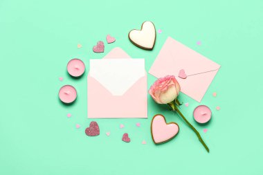 İçinde gül, kurabiye ve yeşil arka planda kalpler olan boş bir mektup. Sevgililer Günü kutlaması