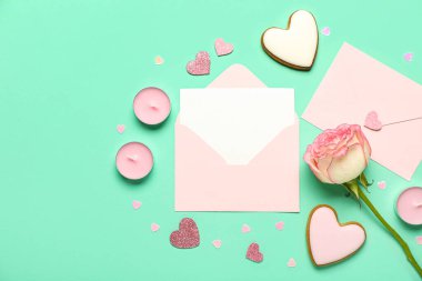 İçinde gül, kurabiye ve yeşil arka planda kalpler olan boş bir mektup. Sevgililer Günü kutlaması