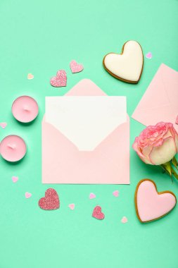 İçinde gül, kurabiye ve yeşil arka planda kalpler olan boş bir mektup. Sevgililer Günü kutlaması