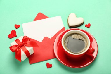Yeşil arka planda kahve, kurabiye ve hediyeli boş bir mektup. Sevgililer Günü kutlaması