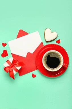 Yeşil arka planda kahve, kurabiye ve hediyeli boş bir mektup. Sevgililer Günü kutlaması