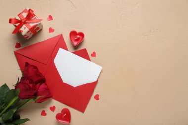 İçinde güller, hediye ve bej arka planda mumlar olan boş bir mektup. Sevgililer Günü kutlaması