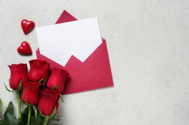 Beyaz arkaplanda güller ve şekerler olan boş bir mektup. Sevgililer Günü kutlaması