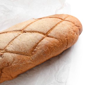 Beyaz arka planda bir somun taze ekmekli kağıt, yakın plan.