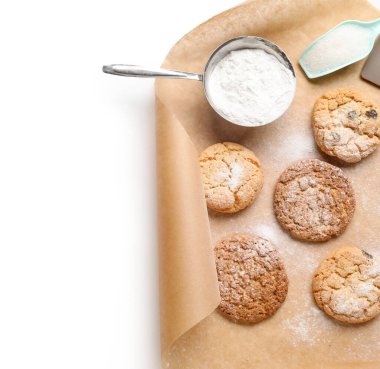 Beyaz zemin üzerinde lezzetli kurabiyeler ve şeker tozu olan bir yaprak kağıt, yakın plan.