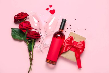 Bir şişe şarap, bardaklar, güller ve pembe arka planda hediye. Sevgililer Günü kutlaması