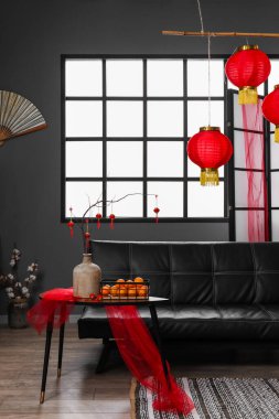 Çin Yeni Yıl kutlamaları için kanepesi, masası ve dekoru olan karanlık oturma odasının içi.