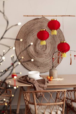 Çin Yeni Yıl kutlamaları için vazo, ağaç dalları ve dekor içeren yemek masası.