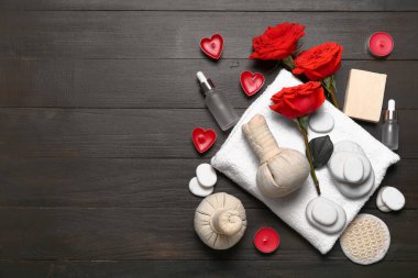 Sevgililer Günü için güzel bir spa kompozisyonu. Ahşap arka planda bitki torbaları, havlu, gül çiçekleri, sabun, taşlar ve mumlar var.
