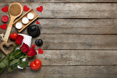 Sevgililer Günü için güzel bir spa kompozisyonu. Tahta arka planda taşlar, mumlar, havlu, fırça ve gül çiçekleri.