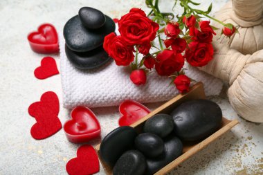 Sevgililer Günü için güzel bir spa kompozisyonu. Gül çiçekleri, taşlar, havlu ve ışık arka planında mumlar.