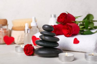 Sevgililer Günü için güzel bir spa kompozisyonu. Masada güller, mumlar ve taşlar var.