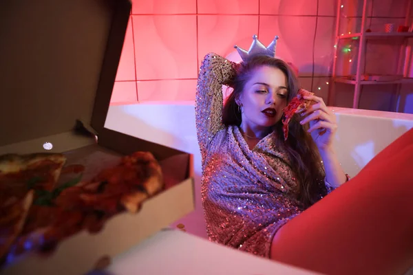Drunk young woman with pizza in bathtub after party