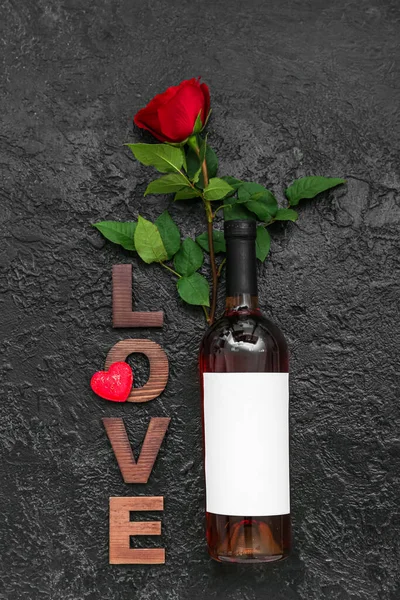 Bottle of wine, rose and word LOVE on dark background. Valentine\'s Day celebration