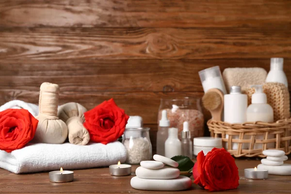 Sevgililer Günü için güzel bir spa kompozisyonu. Tahta zemin üzerinde taşlar, mumlar, gül çiçekleri, havlu ve bitki torbaları var.