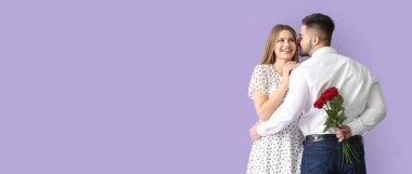 Mutlu genç adam kız arkadaşına çiçek buketini eflatun arkaplanda mesaj için yer açarak verecek. Sevgililer Günü kutlaması