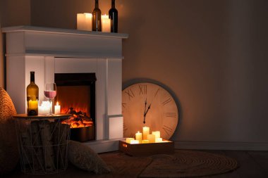 İçinde şömine, yanan mumlar ve şarap olan karanlık bir oturma odası.