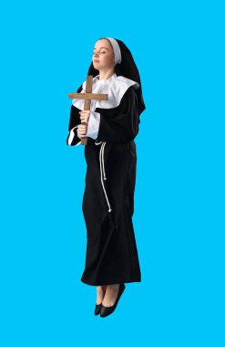 Mavi arka planda çapraz atlama yapan genç rahibe.