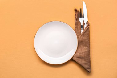 Tabak ve peçete, turuncu arka planda çatal bıçak takımı.